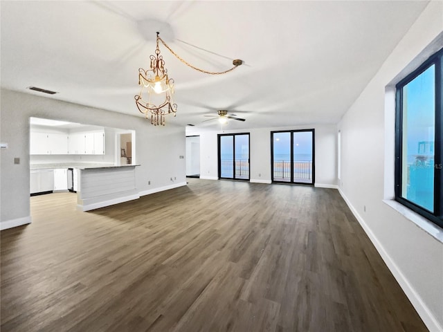 unfurnished living room featuring baseboards, dark wood-style flooring, visible vents, and a notable chandelier