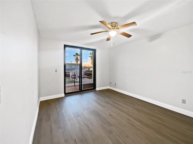 empty room featuring dark wood-type flooring, a ceiling fan, and baseboards