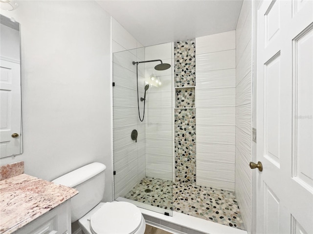 bathroom with a tile shower, vanity, and toilet