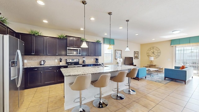 kitchen featuring a breakfast bar area, light stone countertops, appliances with stainless steel finishes, and tasteful backsplash