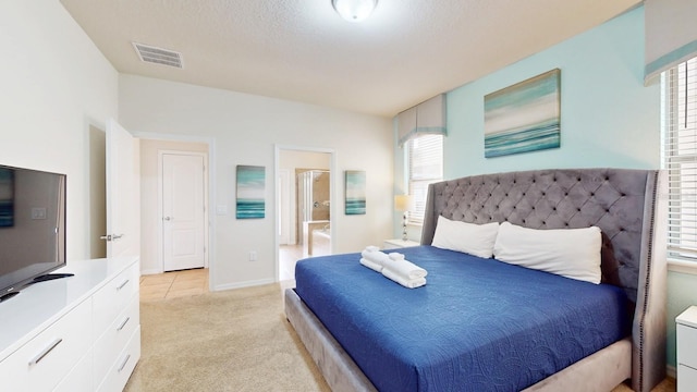 bedroom featuring light carpet and ensuite bathroom