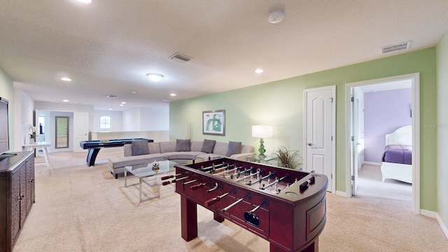 game room with a textured ceiling and light colored carpet