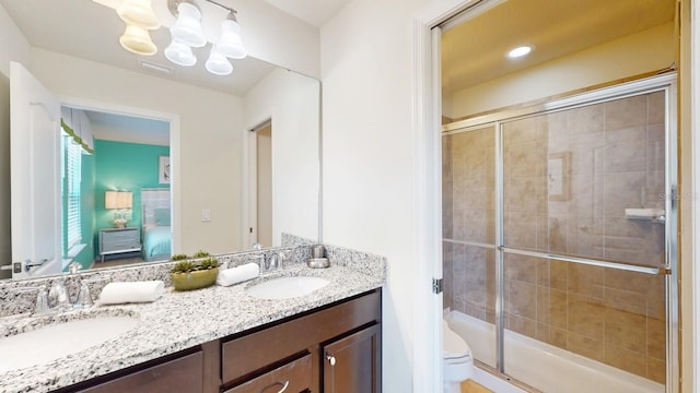 bathroom with an inviting chandelier, a shower with shower door, double vanity, and toilet