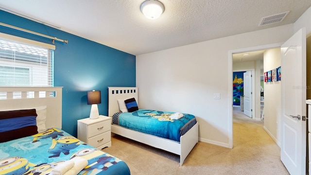 bedroom with a textured ceiling and light colored carpet