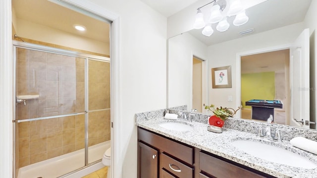 bathroom featuring dual sinks, vanity with extensive cabinet space, an enclosed shower, and toilet