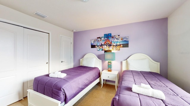 bedroom featuring light colored carpet, visible vents, and a closet