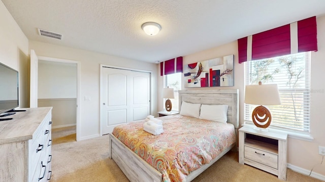 bedroom featuring a closet, a textured ceiling, and light colored carpet