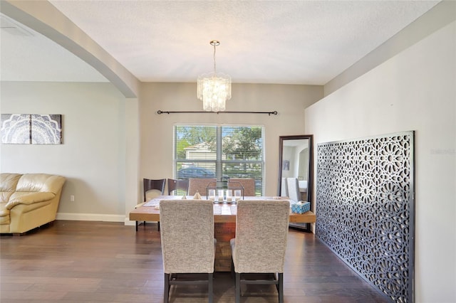 dining space featuring dark wood-type flooring, a chandelier, and a textured ceiling