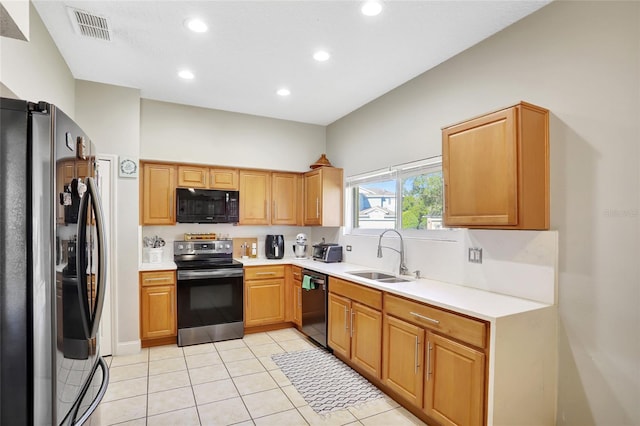 kitchen featuring black appliances, light tile patterned flooring, and sink