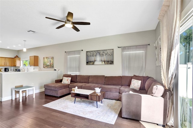 living room featuring dark wood-type flooring, ceiling fan, a healthy amount of sunlight, and sink