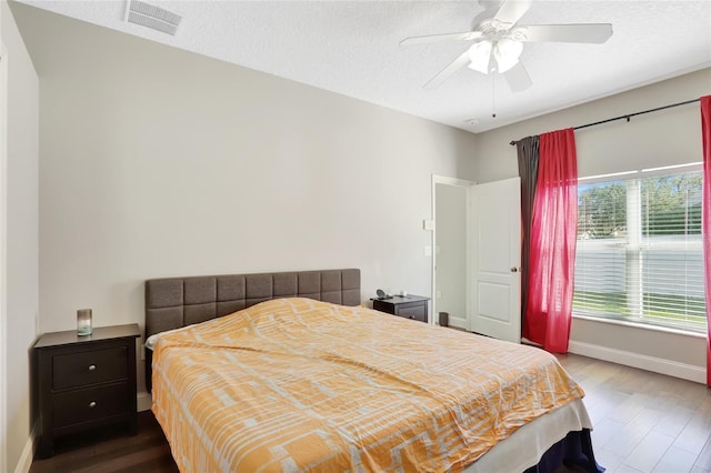 bedroom with ceiling fan, wood-type flooring, and a textured ceiling