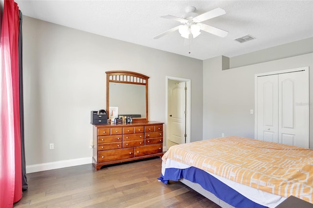 bedroom with ceiling fan, dark hardwood / wood-style flooring, a textured ceiling, and a closet