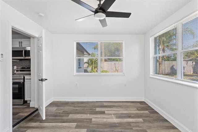 empty room featuring a wealth of natural light, ceiling fan, and hardwood / wood-style flooring