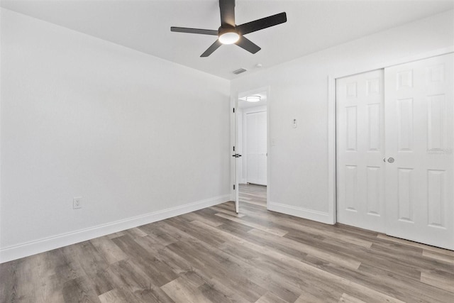 unfurnished bedroom featuring ceiling fan, a closet, and light wood-type flooring