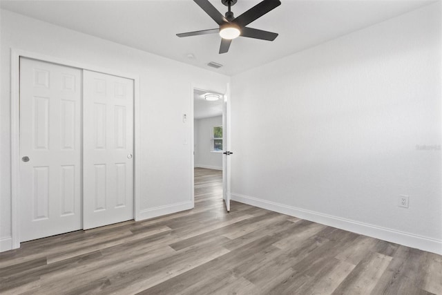 unfurnished bedroom featuring hardwood / wood-style flooring, ceiling fan, and a closet