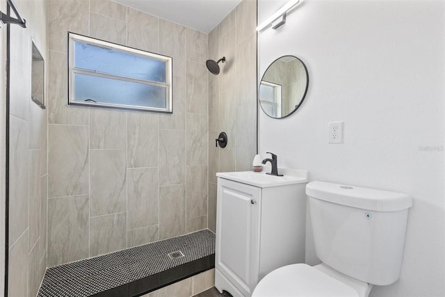 bathroom featuring a tile shower, vanity, and toilet