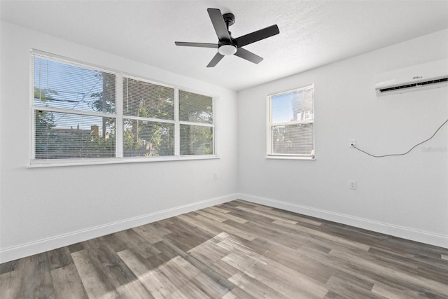 unfurnished room featuring a wall mounted AC, ceiling fan, and hardwood / wood-style flooring