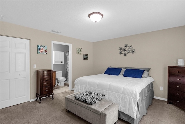 carpeted bedroom with ensuite bathroom and a closet