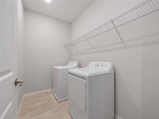 clothes washing area featuring separate washer and dryer and light hardwood / wood-style floors