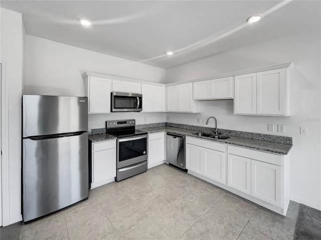 kitchen featuring sink, light tile patterned floors, dark stone countertops, white cabinets, and appliances with stainless steel finishes