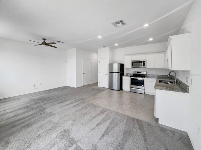 kitchen with appliances with stainless steel finishes, dark stone counters, ceiling fan, sink, and white cabinetry