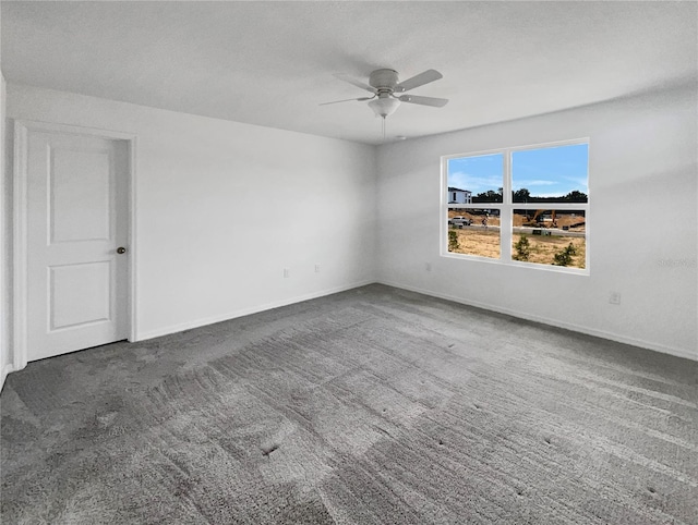 spare room featuring dark colored carpet and ceiling fan