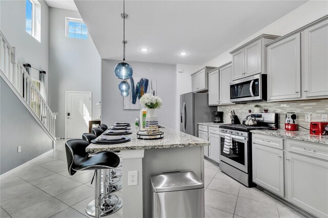 kitchen with stainless steel appliances, tasteful backsplash, light tile floors, and a kitchen island