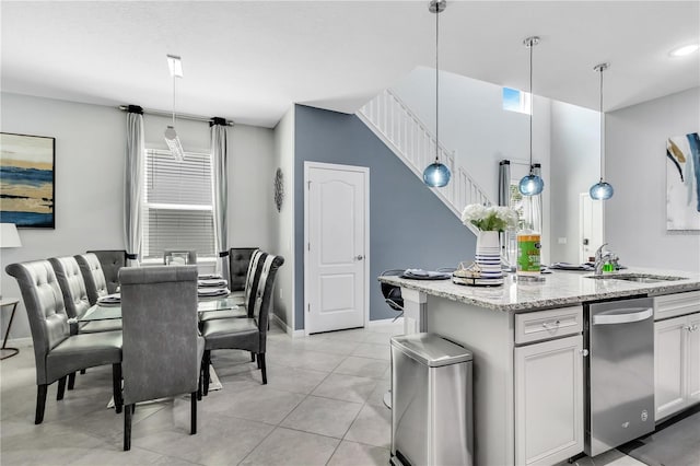 kitchen featuring white cabinetry, light stone countertops, a kitchen island, decorative light fixtures, and light tile floors