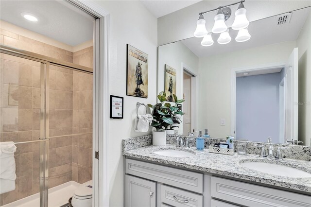 bathroom with a shower with shower door, toilet, a chandelier, and double sink vanity