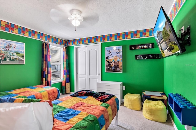 carpeted bedroom with ceiling fan, a closet, and a textured ceiling