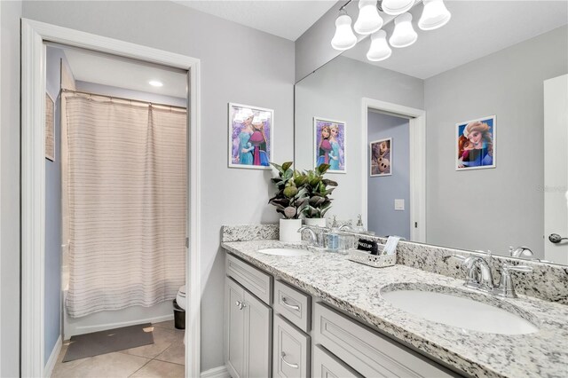 bathroom featuring tile floors, a notable chandelier, toilet, and double sink vanity