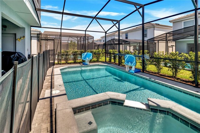 view of swimming pool featuring glass enclosure and an in ground hot tub