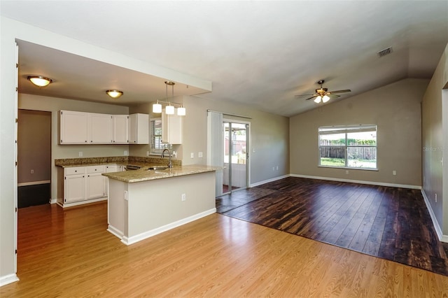 kitchen with white cabinetry, sink, kitchen peninsula, pendant lighting, and light wood-type flooring