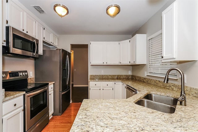 kitchen featuring stainless steel appliances, white cabinetry, light hardwood / wood-style floors, and sink