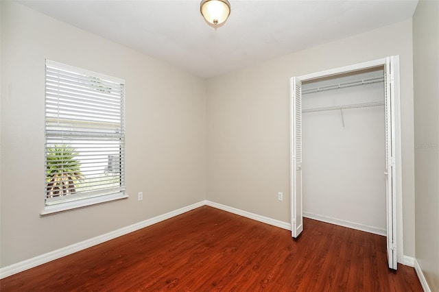 unfurnished bedroom with dark hardwood / wood-style floors and a closet