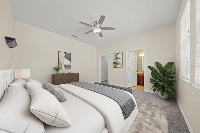 bedroom with ceiling fan, ensuite bathroom, and light colored carpet