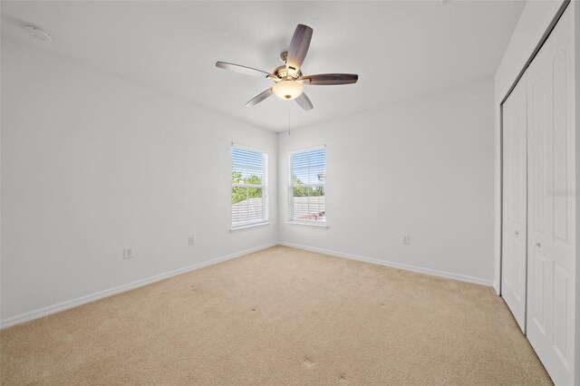 unfurnished bedroom with ceiling fan, a closet, and light carpet