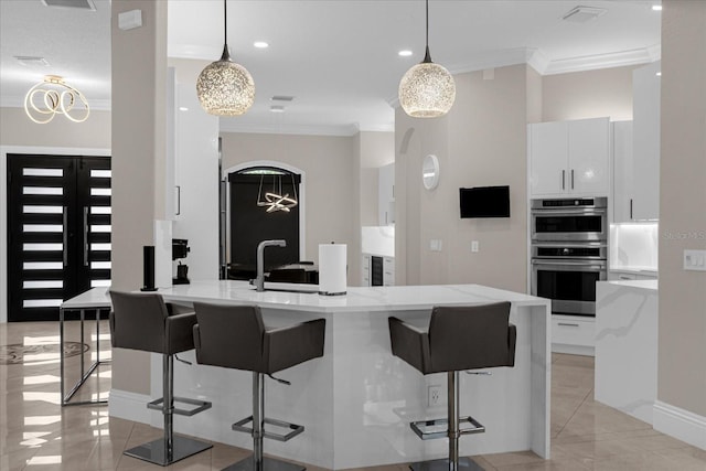 kitchen featuring white cabinetry, hanging light fixtures, ornamental molding, and stainless steel double oven