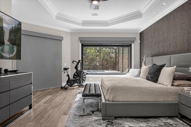 bedroom featuring a raised ceiling, ornamental molding, and light hardwood / wood-style flooring