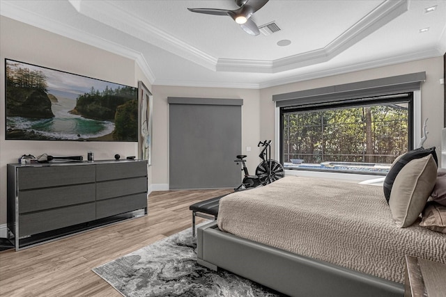 bedroom featuring crown molding, ceiling fan, a tray ceiling, and light hardwood / wood-style flooring