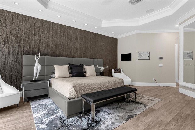 bedroom featuring crown molding, a tray ceiling, and light wood-type flooring