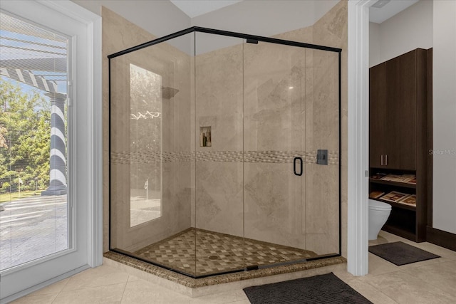 bathroom featuring an enclosed shower, tile patterned floors, and toilet