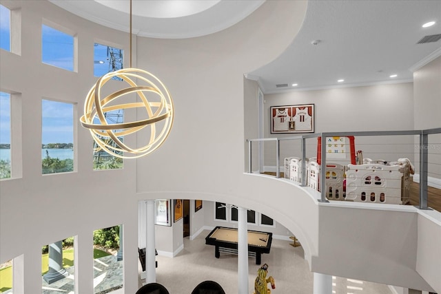 staircase featuring a towering ceiling, a wealth of natural light, and ornamental molding