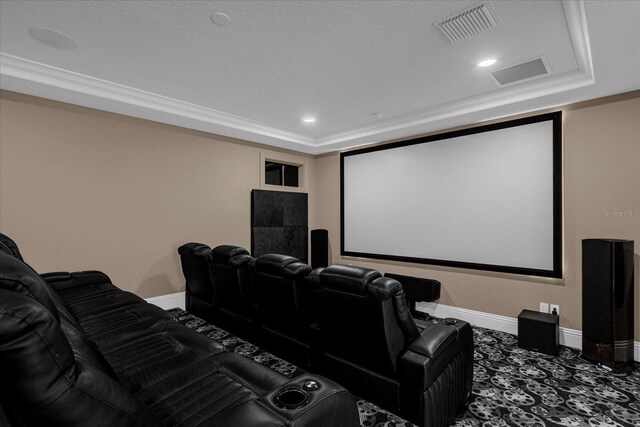 carpeted home theater room featuring a raised ceiling and crown molding