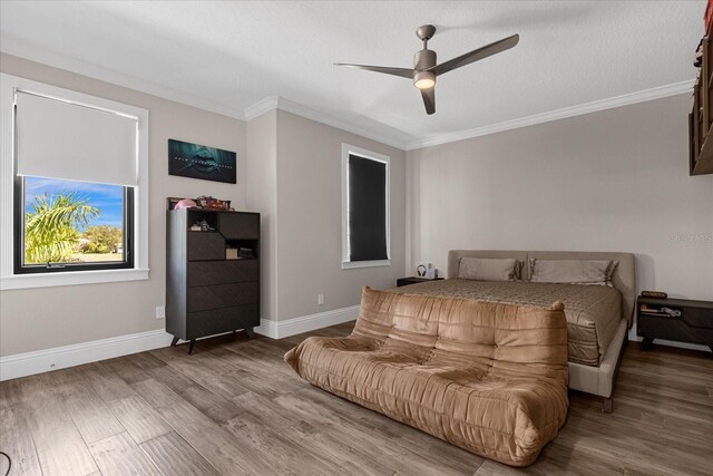 bedroom featuring hardwood / wood-style floors, ornamental molding, and ceiling fan