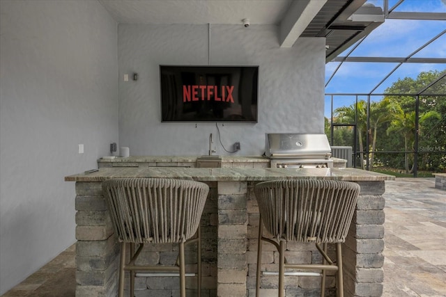 view of patio / terrace featuring an outdoor kitchen, an outdoor bar, grilling area, and glass enclosure