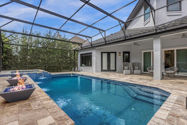 view of swimming pool with a patio, pool water feature, glass enclosure, an outdoor fire pit, and french doors