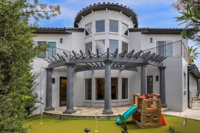 back of property with a pergola and a playground