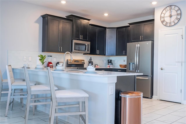 kitchen with stainless steel appliances, backsplash, a kitchen bar, and kitchen peninsula