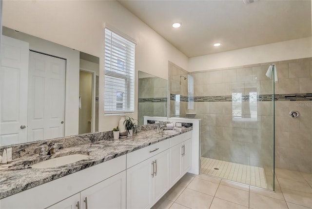 bathroom with a tile shower, vanity, and tile patterned floors